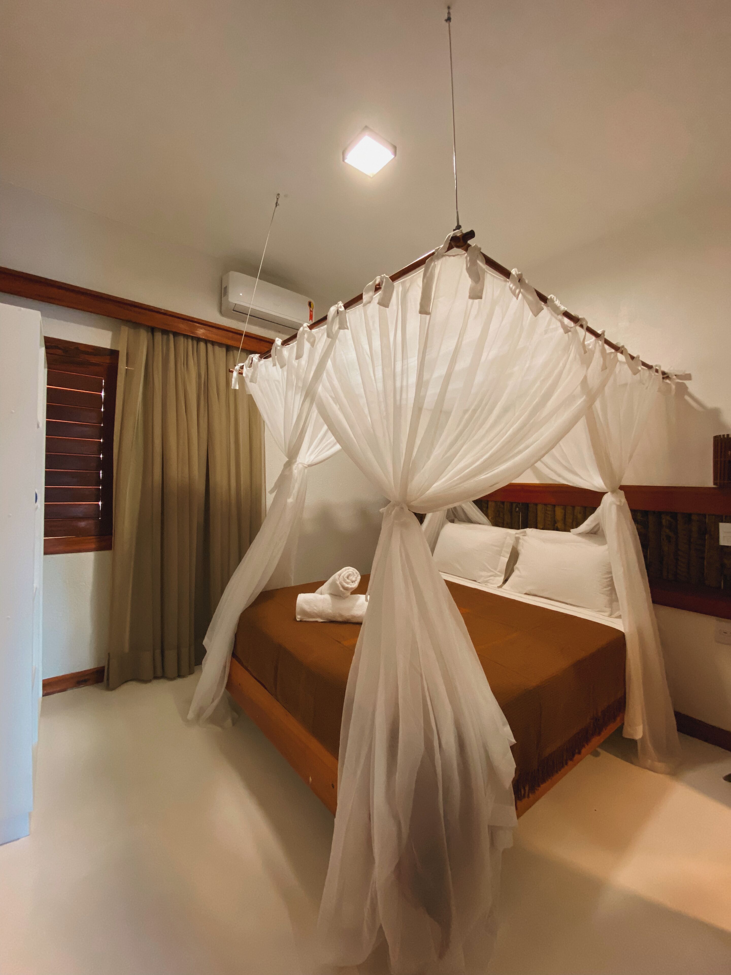 Ein Schlafzimmer mit Himmelsbett, Nachttisch, gerolltem Handtuch und Beistelltisch.