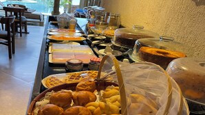 A buffet setup with various food items, including pastries and a waffle. - Pousada Velho Chico (Amontada)