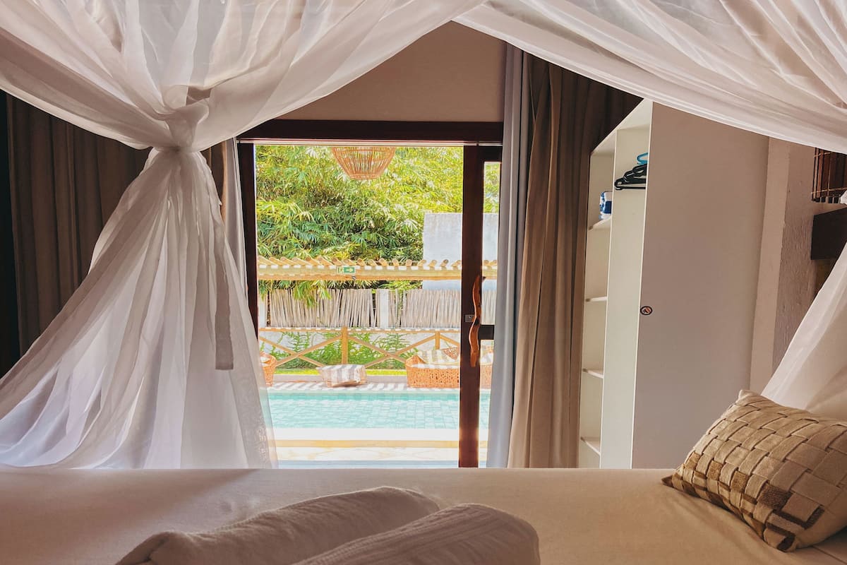 Une chambre avec un lit, une serviette enroulée, un oreiller et une vue sur une piscine extérieure.