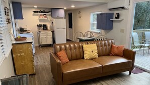 Un espace de vie compact comprenant un canapé en cuir marron, une kitchenette et un coin repas.