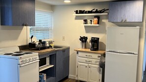 Une cuisine de taille réduite équipée d’une cuisinière, d’un four, d’un four à micro-ondes et d’un réfrigérateur.