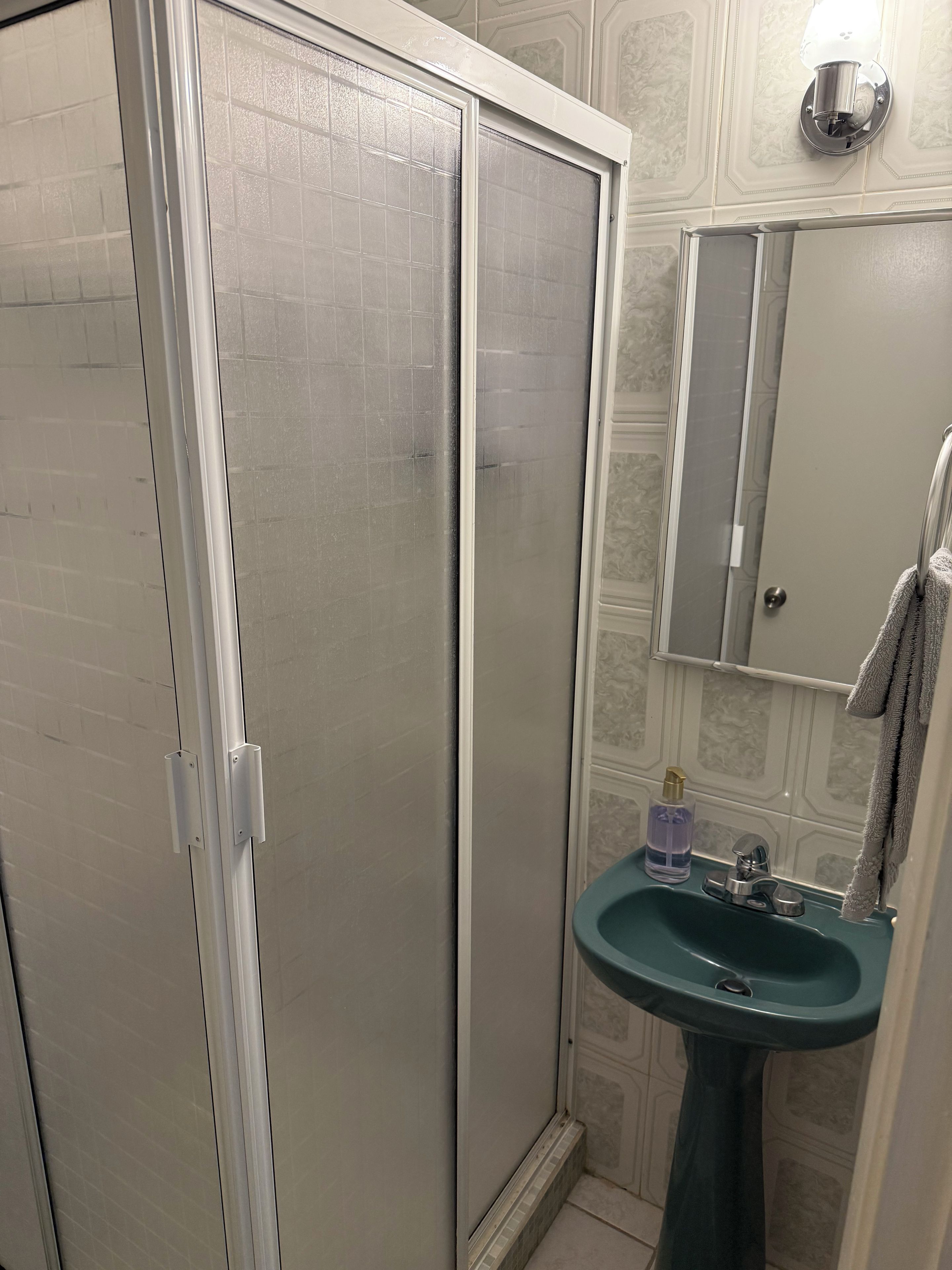 Un baño con cabina de ducha, lavabo y espejo.