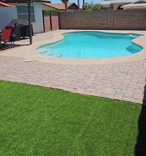 A backyard with a swimming pool, a brick patio, and artificial grass. - Make The Palm Home your home and the best pleasant stay with awesome amenities (Glendale)
