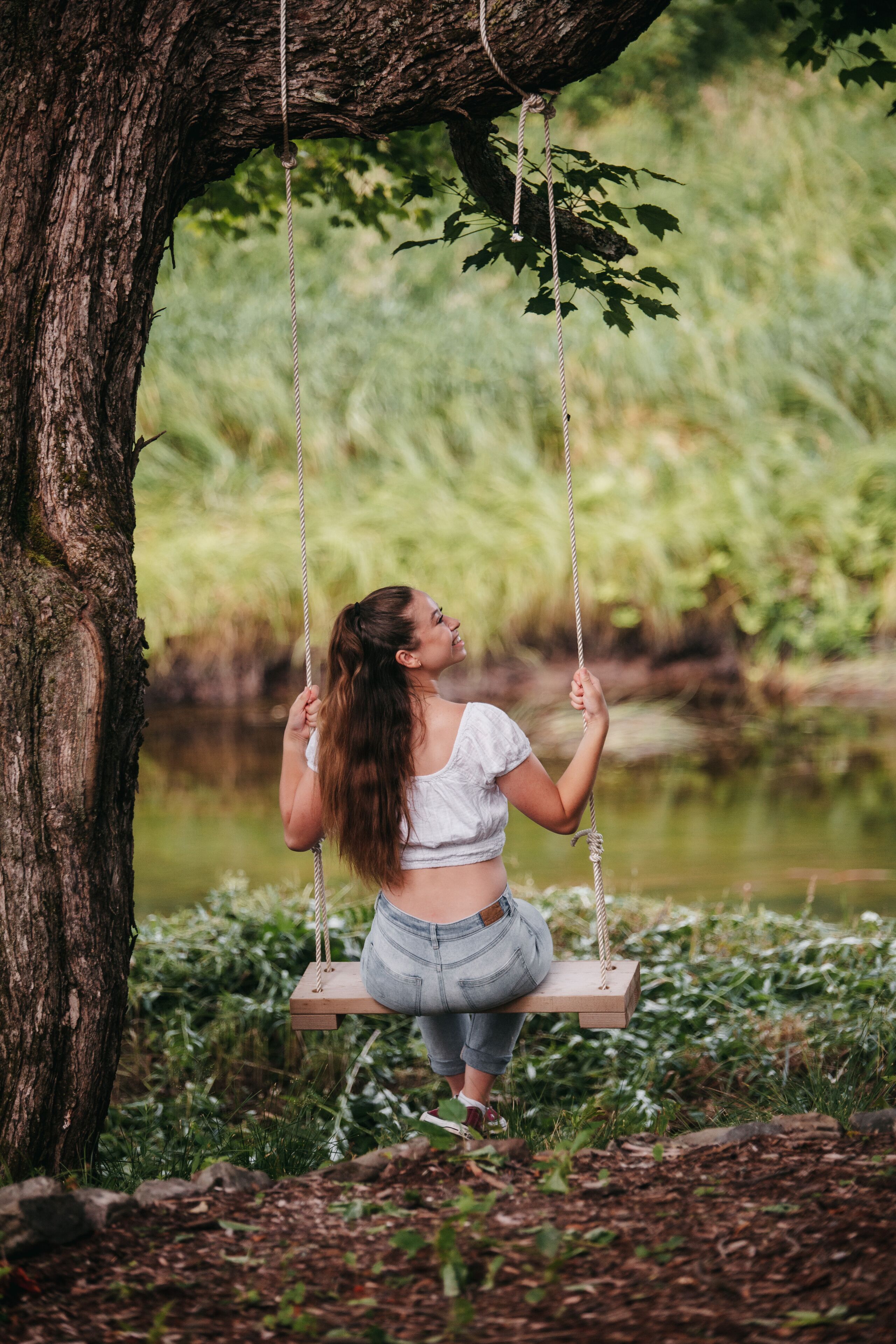 Una mujer sentada en un columpio colgando de un árbol.