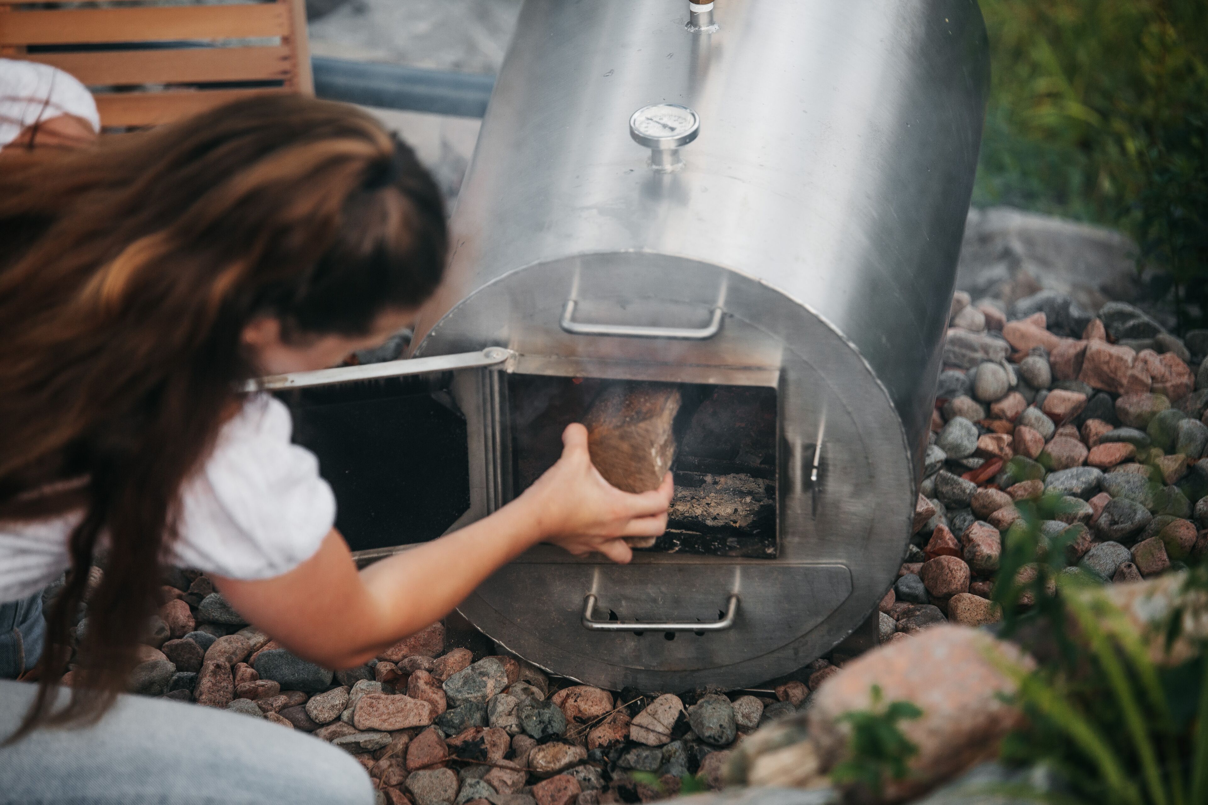 A person opening a stainless steel outdoor grill.