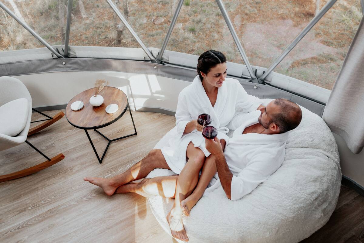 A couple in a cozy, modern room with a large window, a round wooden table, and a comfortable seating area.