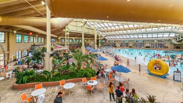 An indoor swimming pool with a covered area, seating, and a water slide.