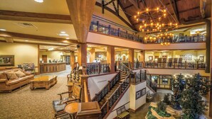 A multi-level hotel lobby with wooden beams, a central staircase, and a Christmas tree.