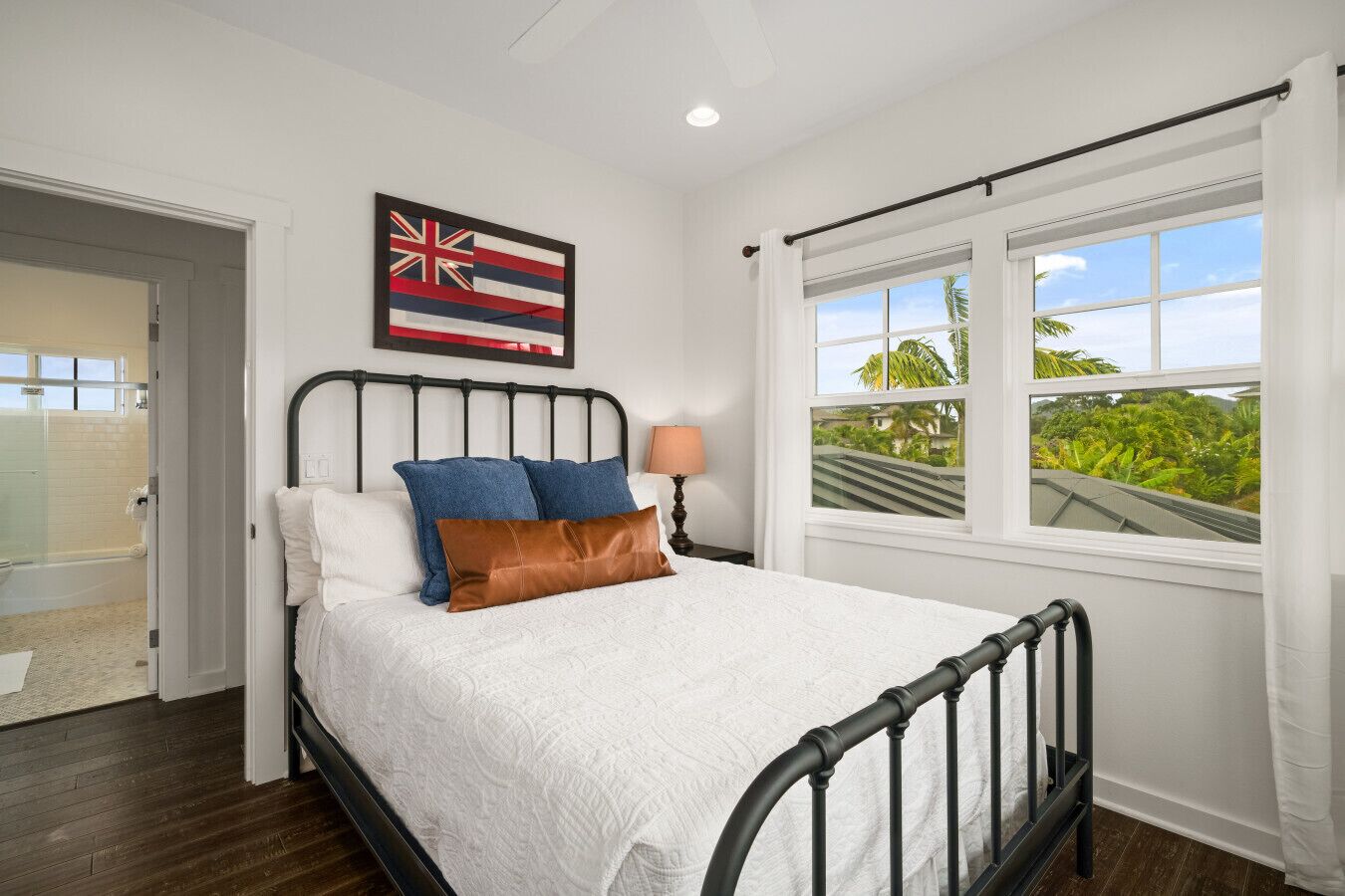 A bedroom with a bed, a window with a view, a door, and a wall-mounted flag.