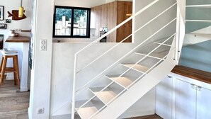 A modern interior with a spiral staircase, wooden flooring, and a kitchen area with bar stools.