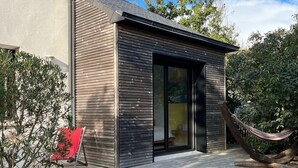 A modern house with a wooden deck, a hammock, and a red chair.