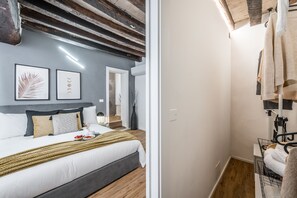 A modern bedroom with a bed, a bedside table, and a nightstand. There is a wooden ceiling and a white wall with framed artwork. - [Design & History Downtown] Hello Beautiful (Modena)