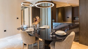 Un coin repas moderne avec une table en verre, quatre chaises et un vase contenant des fleurs séchées.