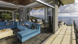 Een moderne woonkamer met een blauwe modulaire bank, een salontafel en uitzicht op de oceaan.