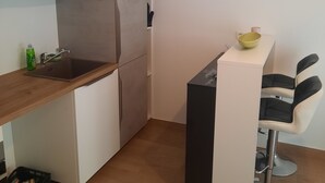 A compact kitchen with a wooden countertop, a sink, and a small bar area with two stools. - Studio de 22m 2 (Etrembières)