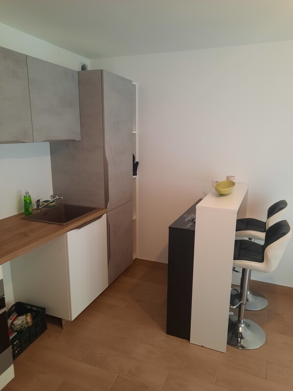 A compact kitchen with a wooden countertop, a sink, and a small bar area with two stools.