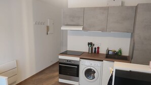 A compact kitchen with a built-in oven, a washing machine, and a countertop with kitchen utensils. - Studio de 22m 2 (Etrembières)