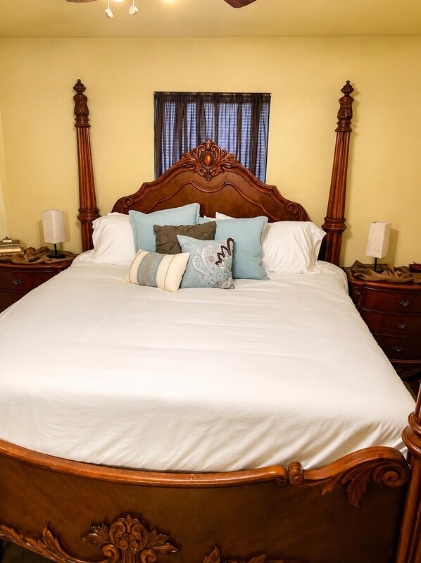 A large bed with a wooden headboard and footboard, flanked by nightstands with lamps, in a room with a window and curtains. - “Wine Down” in our beautiful wine themed townhome.
(Ponchatoula)