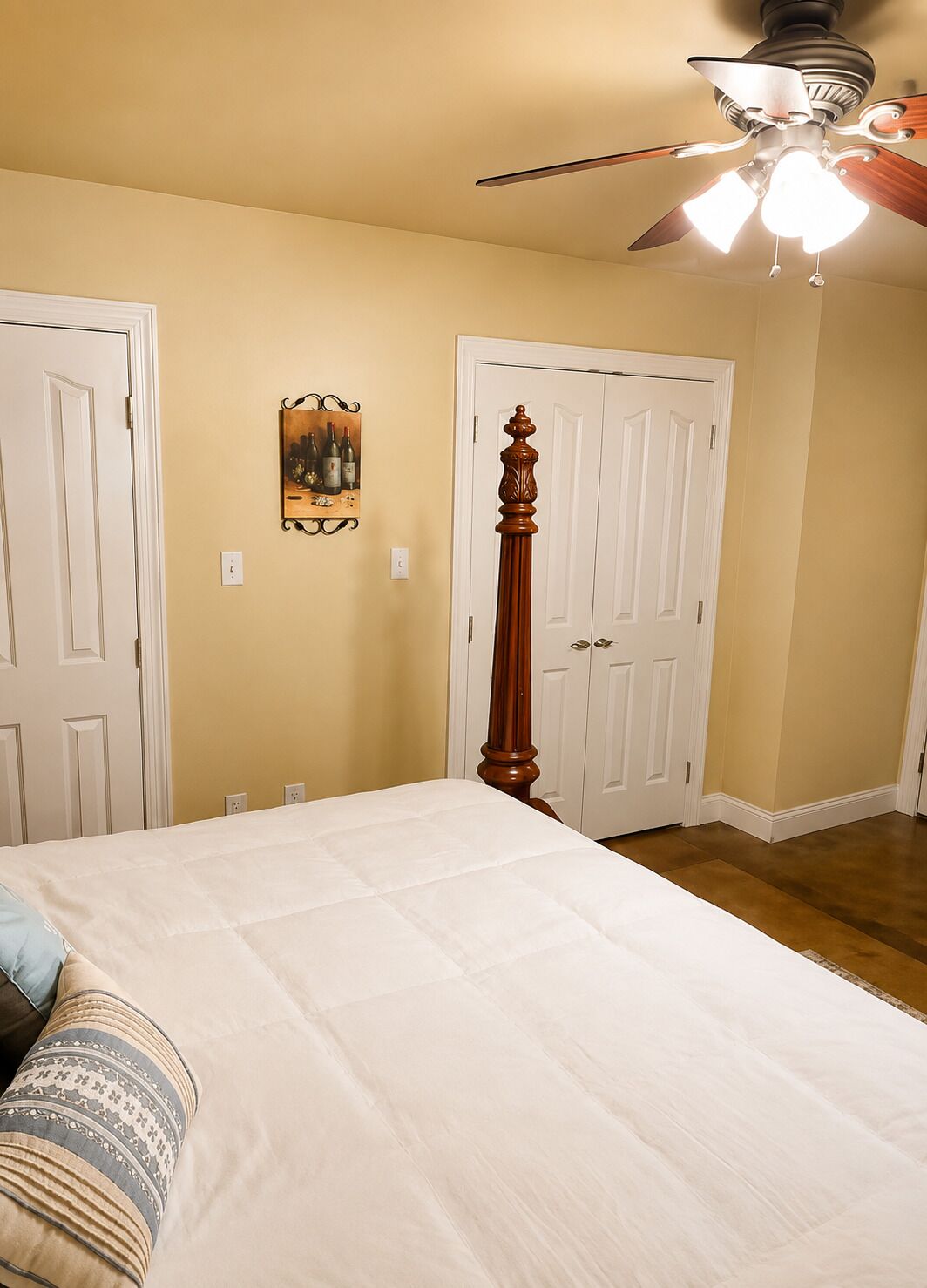 Ein Schlafzimmer mit einem Bett, einem Deckenventilator und zwei Türen.