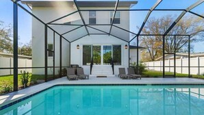 Een modern huis met een glazen patio en een zwembad.