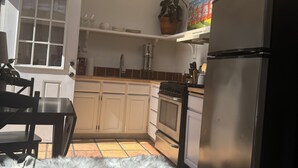 A kitchen with white cabinets, a black refrigerator, a stove, and a skylight. - Cozy Historical Cottage In Petaluma (Petaluma)