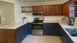 A kitchen with dark blue cabinets, a stainless steel stove, a microwave, and a coffee maker. - Relax in  style! 3 BR ranch near downtown! FENCED yard! PETS welcome (Knoxville)