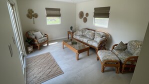 A living room with a sofa, two armchairs, a coffee table, and a floor lamp. There are two windows with blinds, a ceiling fan, and a door. - Relax in  style! 3 BR ranch near downtown! FENCED yard! PETS welcome (Knoxville)