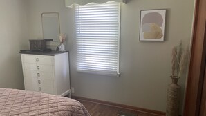 A bedroom with a bed, dresser, window with blinds, and a vase with dried plants. - Relax in  style! 3 BR ranch near downtown! FENCED yard! PETS welcome (Knoxville)