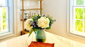 Eine Küche mit Marmorarbeitsplatte, einem Blumenvasen und einer Pendelleuchte.