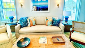 Ein Wohnzimmer mit einer Couch, zwei Sesseln, einem Couchtisch und einer Chandelier.