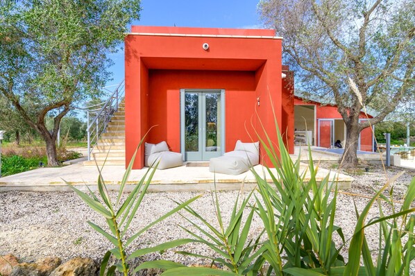 A modern red building with a glass door and two white cushions outside.