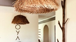 Un pasillo con una mesa de madera rústica, un paraguas de paja colgante y una escultura de ramas.