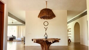 Una habitación amplia con una gran mesa de madera en el centro, una lámpara colgante y una pared con las letras 'OYA'.