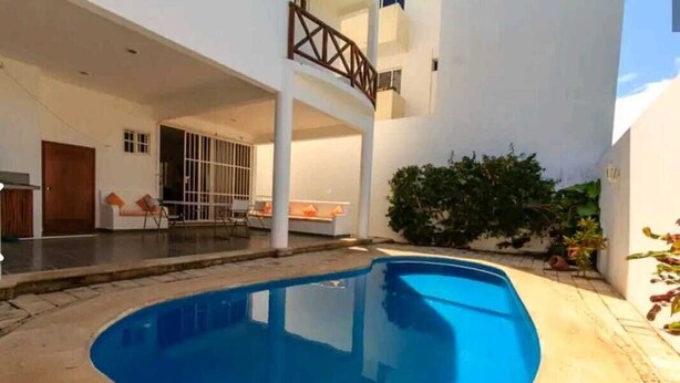 A modern house with a swimming pool, a covered patio, and a staircase leading to an upper level.