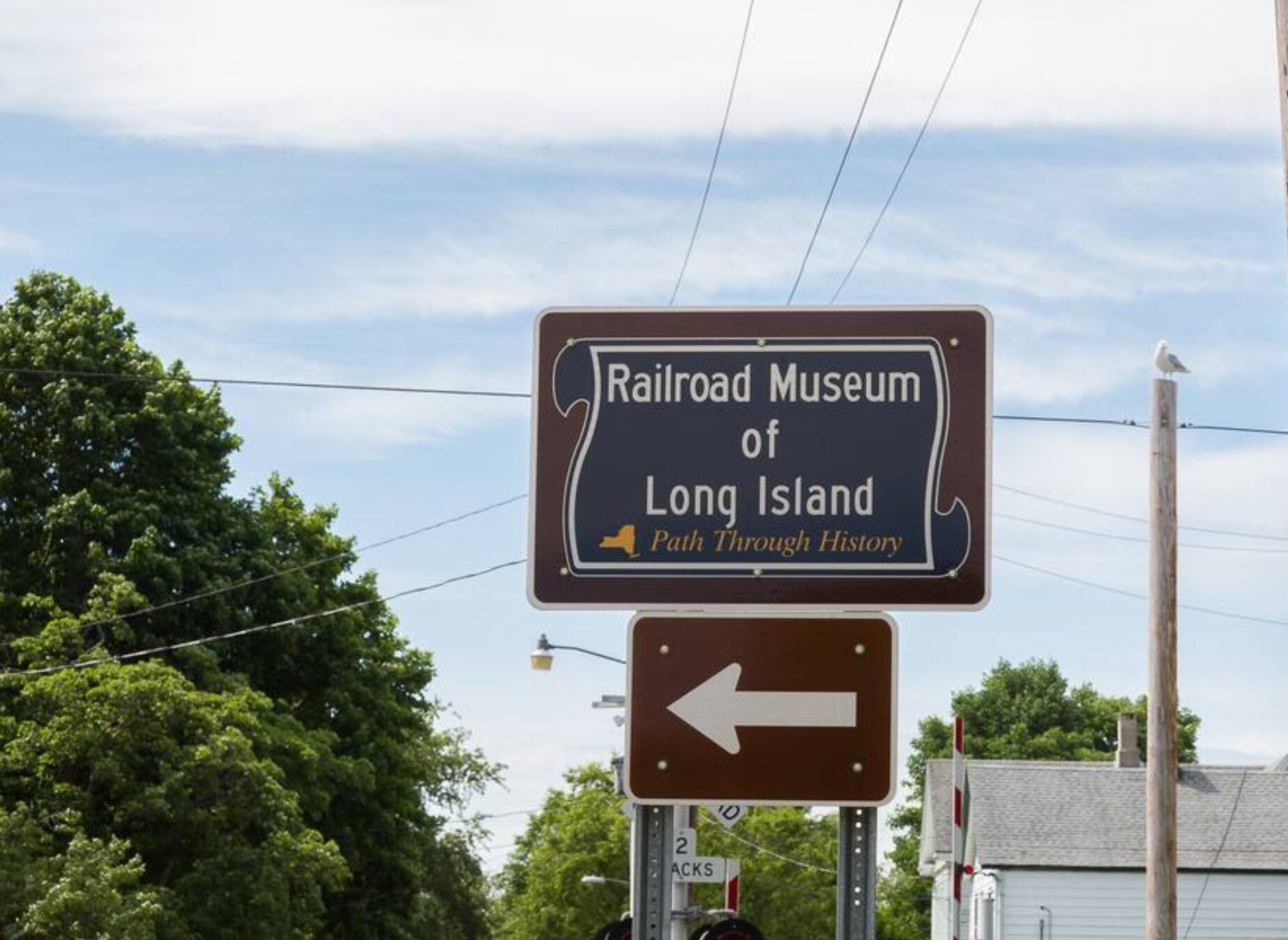 Opastekyltti, jossa on Long Islandin rautatiemuseon nimi ja nuoli, joka osoittaa suunnan.