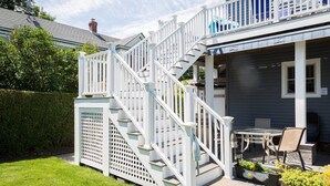 A two-story house with a white staircase, a covered patio with outdoor furniture, and a fenced yard. - Harbor Heights  (Greenport)