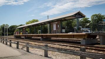 Ein Bahnsteig mit überdachtem Wartebereich, Gleisen und einem Zaun.