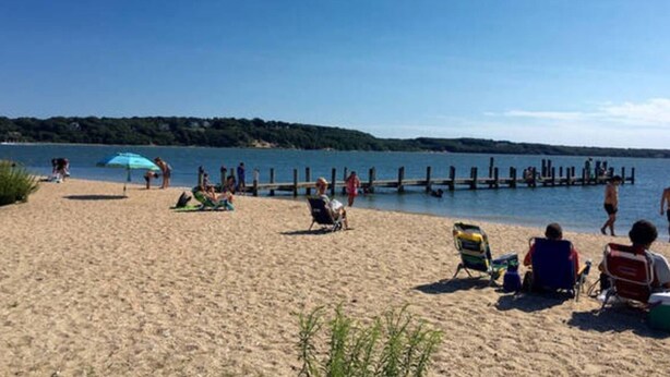 A beach with people relaxing on chairs and sunbathing. - Harbor Heights  (Greenport)