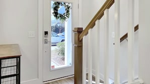 A white door with a glass panel and a wreath, leading to a wooden staircase.
