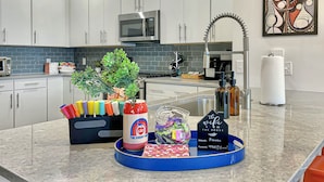 A modern kitchen with white cabinets, a microwave, and a coffee machine. There is a tray with a plant, a can, and a sign for wifi.