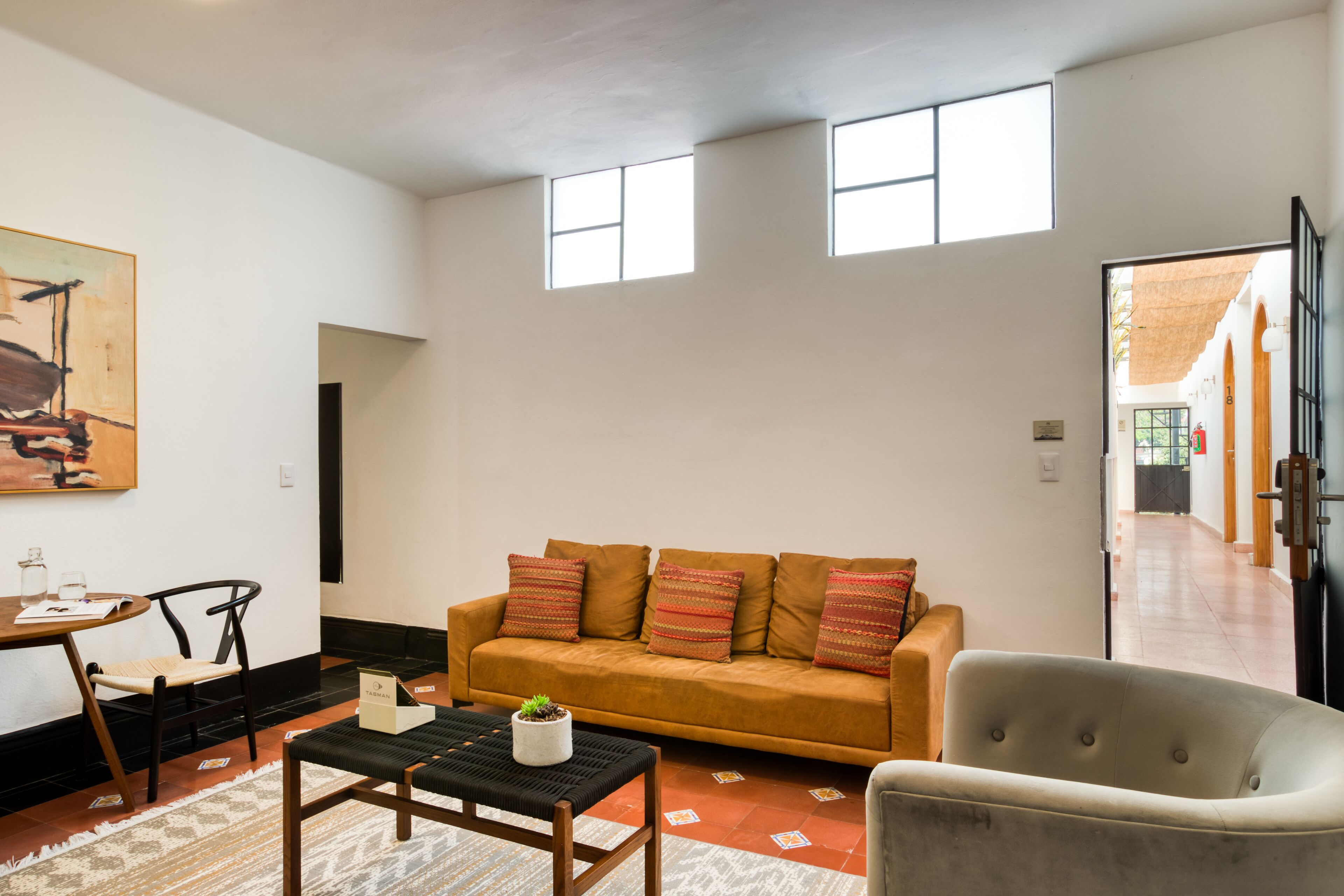 A living room with a sofa, a chair, a coffee table, and a painting on the wall.