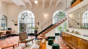 A spacious lobby with a staircase, seating area, and a reception desk. - Santa Casa by Tasman (Mexico City)