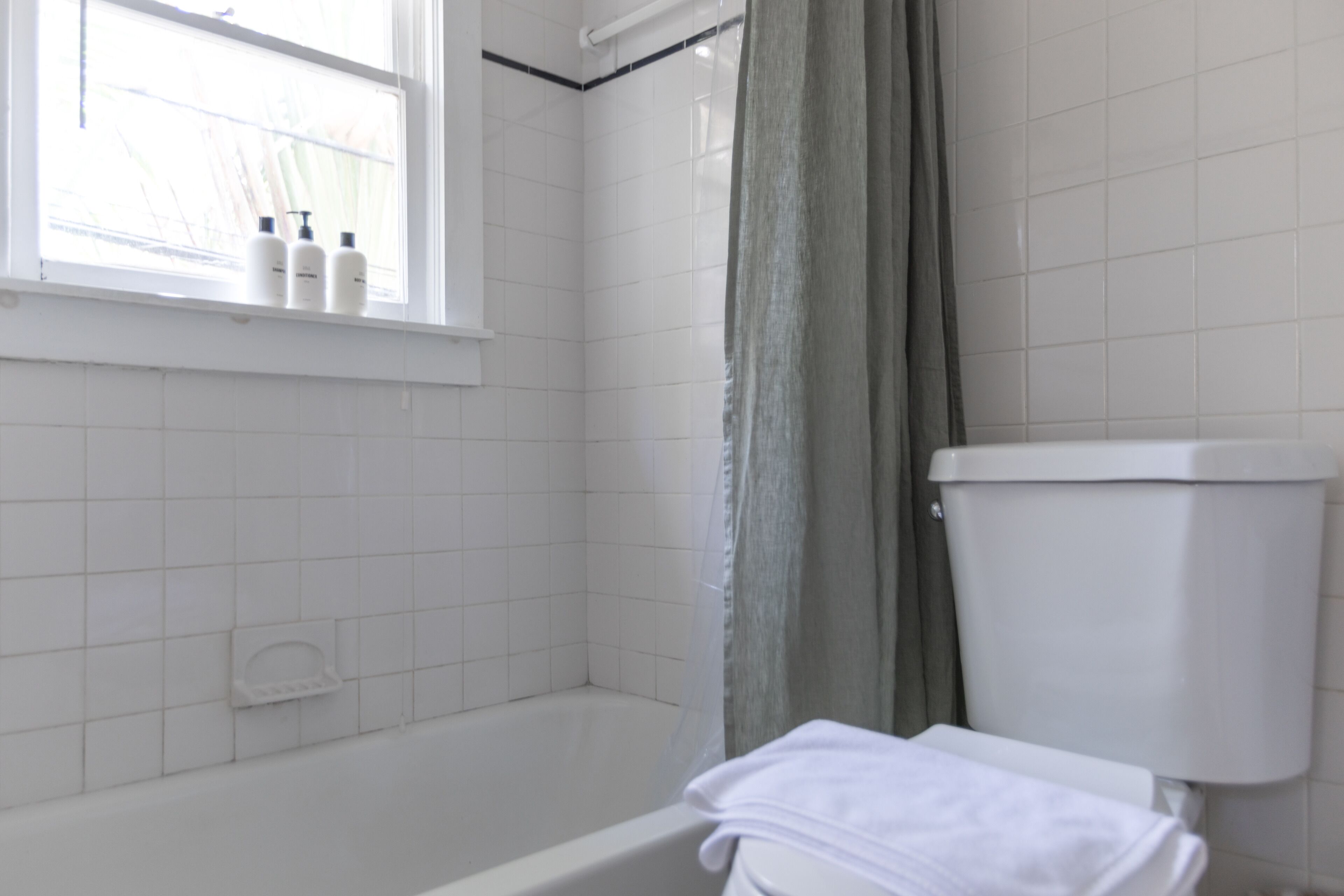A bathroom with a bathtub, toilet, and window.