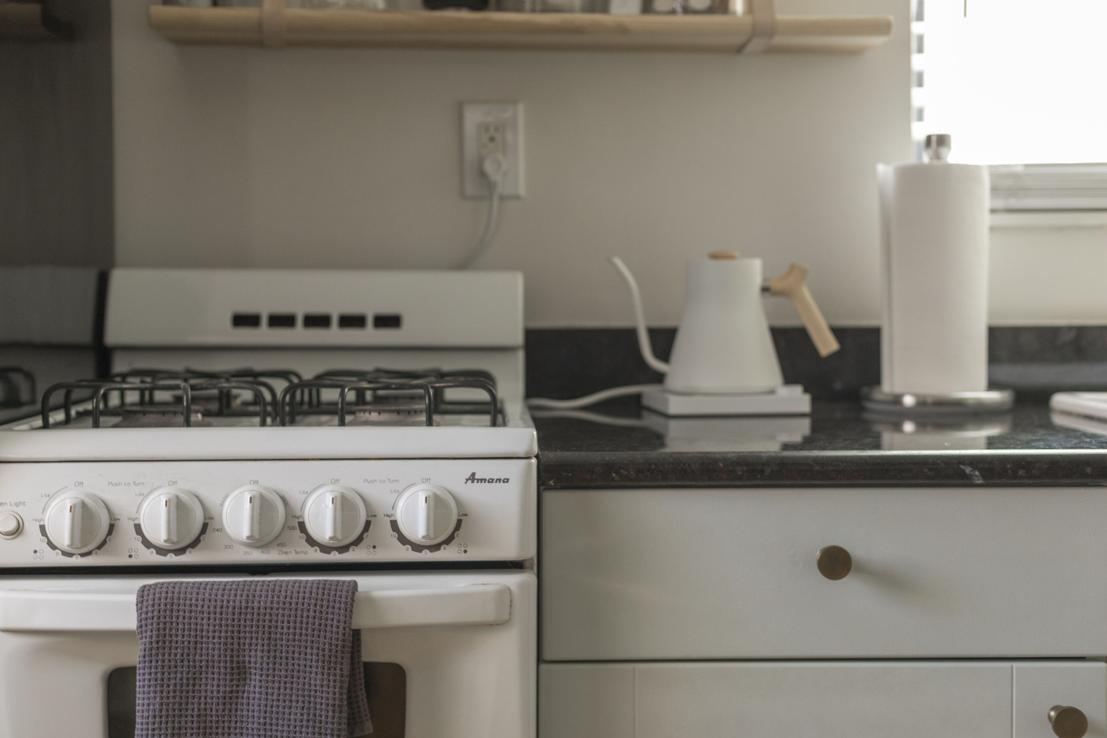 A kitchen with a white stove, a countertop, and a drawer.
