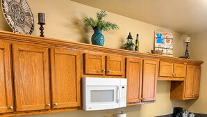 A kitchen with wooden cabinets, a white stove, a microwave, and a sink. - Relax in our beautiful New Orleans themed townhome

 (Ponchatoula)