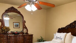 A bedroom with a wooden bed, a large mirror, a ceiling fan, and a decorative rug. - Relax in our beautiful New Orleans themed townhome

 (Ponchatoula)
