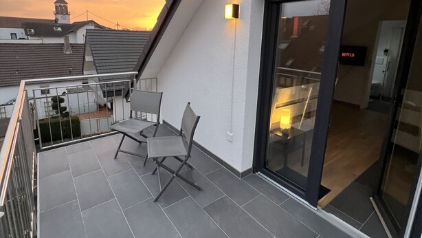 Terraza en la azotea con zona de estar y puerta de vidrio que da a un espacio interior.