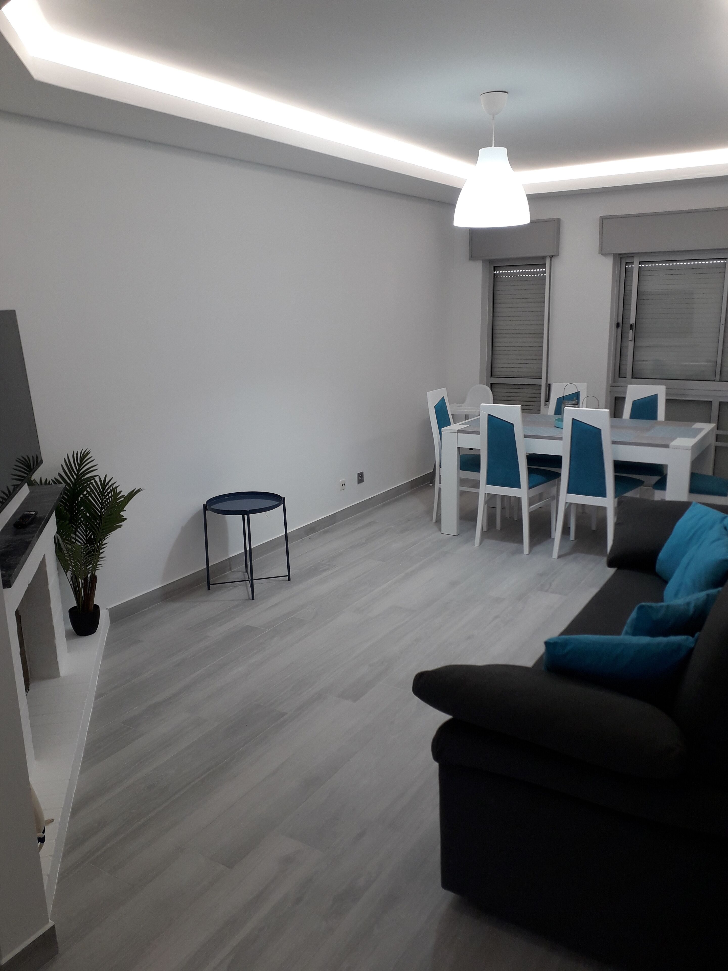 A modern living room with a black sofa, a dining table with chairs, and a small round table with a chair.