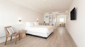 A modern bedroom with a large bed, a bedside table, a chair, and a TV mounted on the wall.
