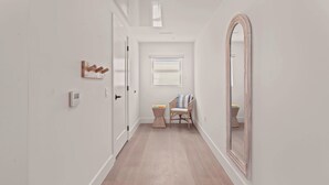 A hallway with a wooden floor, a wooden chair, a small table, and a mirror on the wall. - Casa SOBE (Miami Beach)